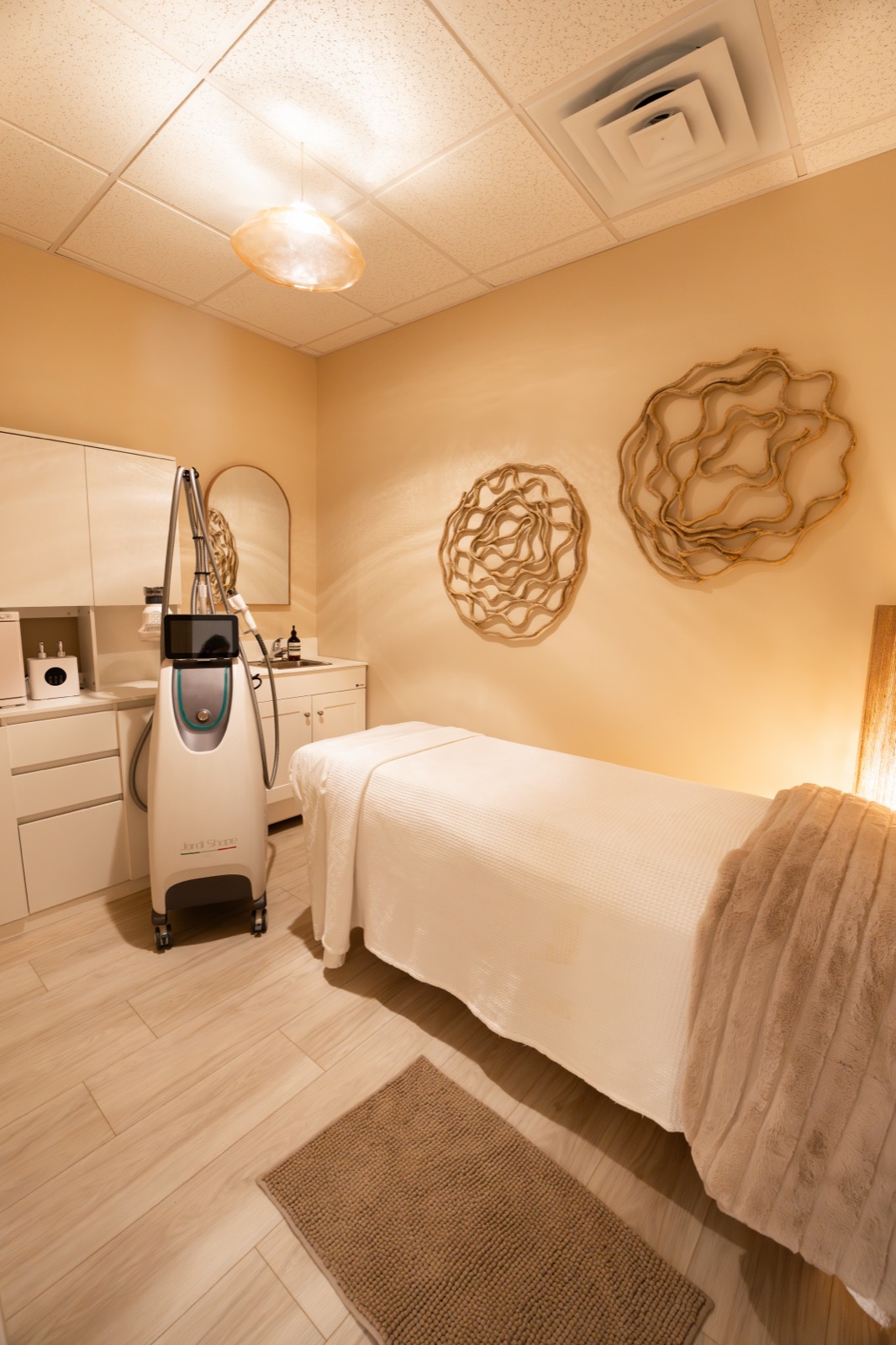Warmly lit treatment room at Rêve Wellness with a treatment table and wooden wall art